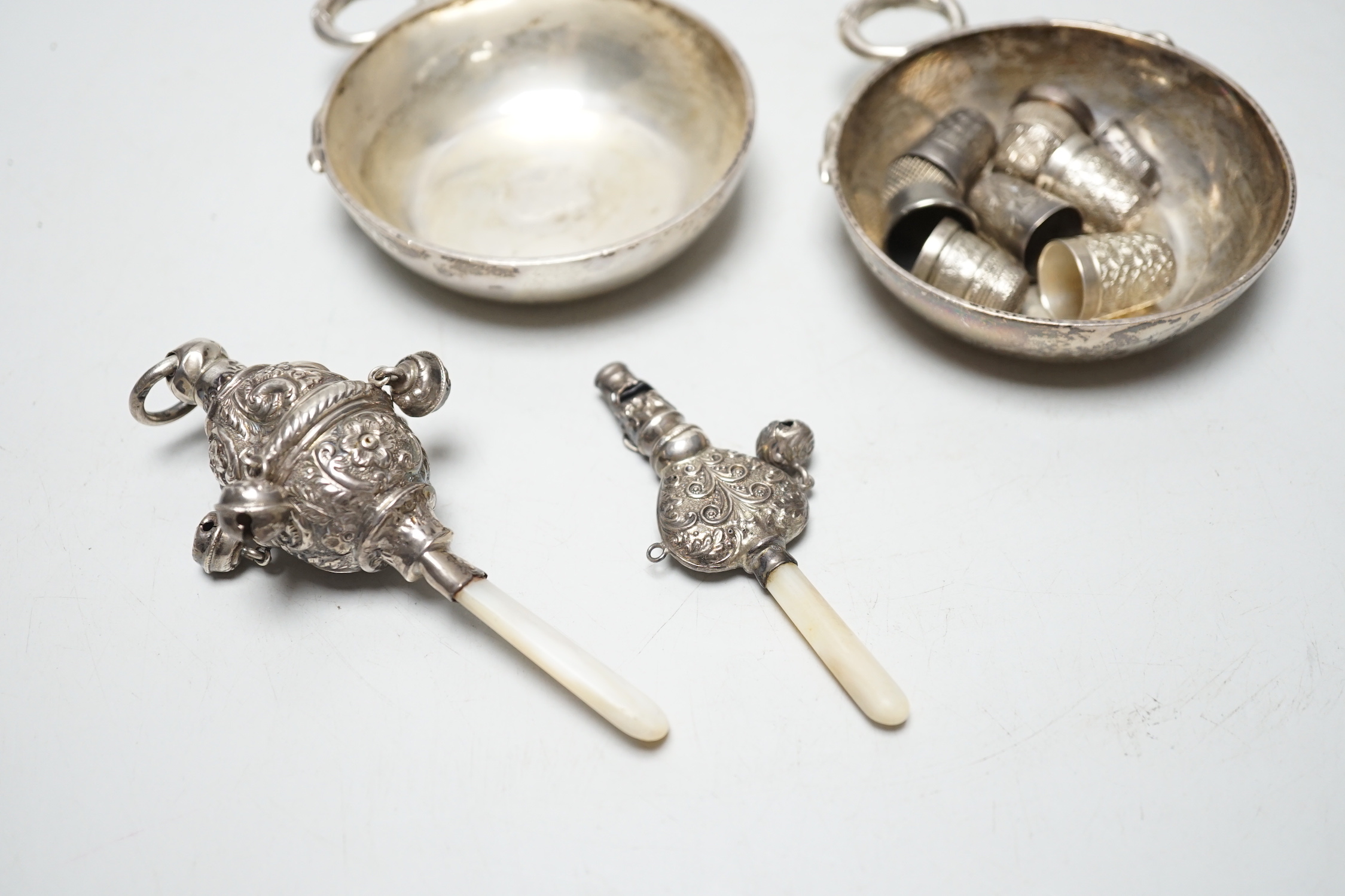 A pair of George V silver taste vin, D & J Welby Ltd, diameter 82mm, a late Victorian mother of pearl handled repousse silver child's rattle, one other larger similar silver rattle and eight thimbles including five silve